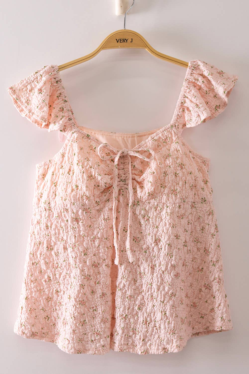 Blushing Prairie floral babydoll top available in blush and white with ruffle flutter sleeves and feminine tie-front neckline.