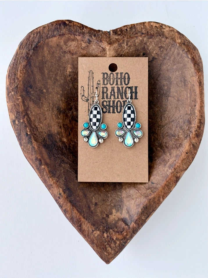 Black and white checkered western drop earrings with turquoise and iridescent stone accents displayed on a rustic wooden heart tray