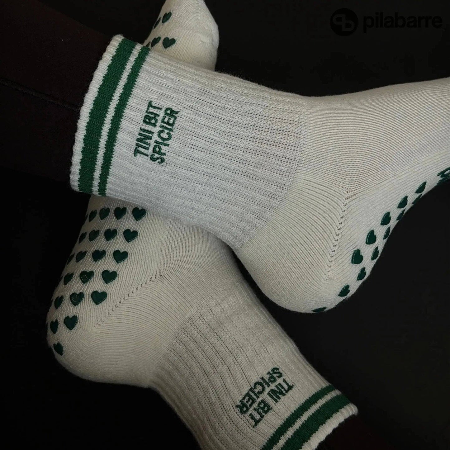 White and green Pilates grip socks with striped ribbed cuffs, embroidered chili pepper detail and green non-slip grips on the soles.