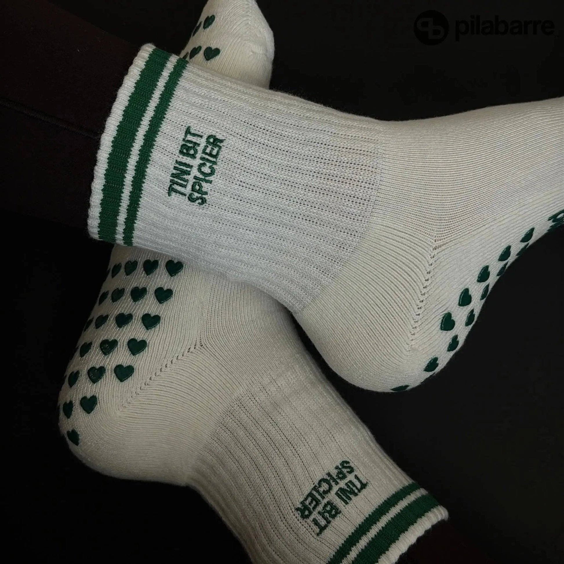 White and green Pilates grip socks with striped ribbed cuffs, embroidered chili pepper detail and green non-slip grips on the soles.