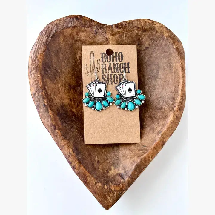 Turquoise western drop earrings featuring playing card designs and turquoise-inspired stone accents displayed on a rustic heart-shaped tray