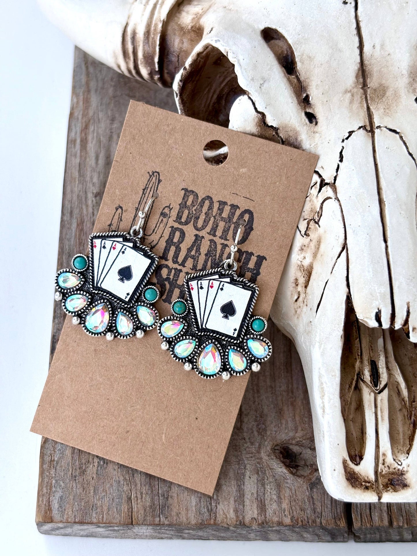 Turquoise western drop earrings featuring playing card designs and turquoise-inspired stone accents displayed on a rustic heart-shaped tray