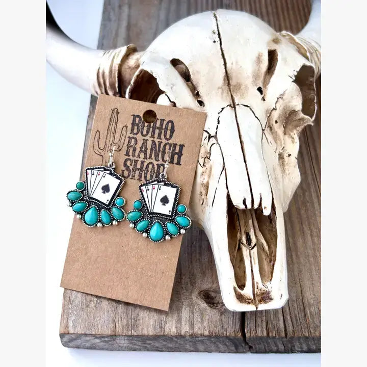 Turquoise western drop earrings featuring playing card designs and turquoise-inspired stone accents displayed on a rustic heart-shaped tray