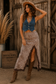 Women's cheetah print maxi skirt featuring ruched detailing, brown lace splicing and a front slit styled with cowboy boots and a denim vest.