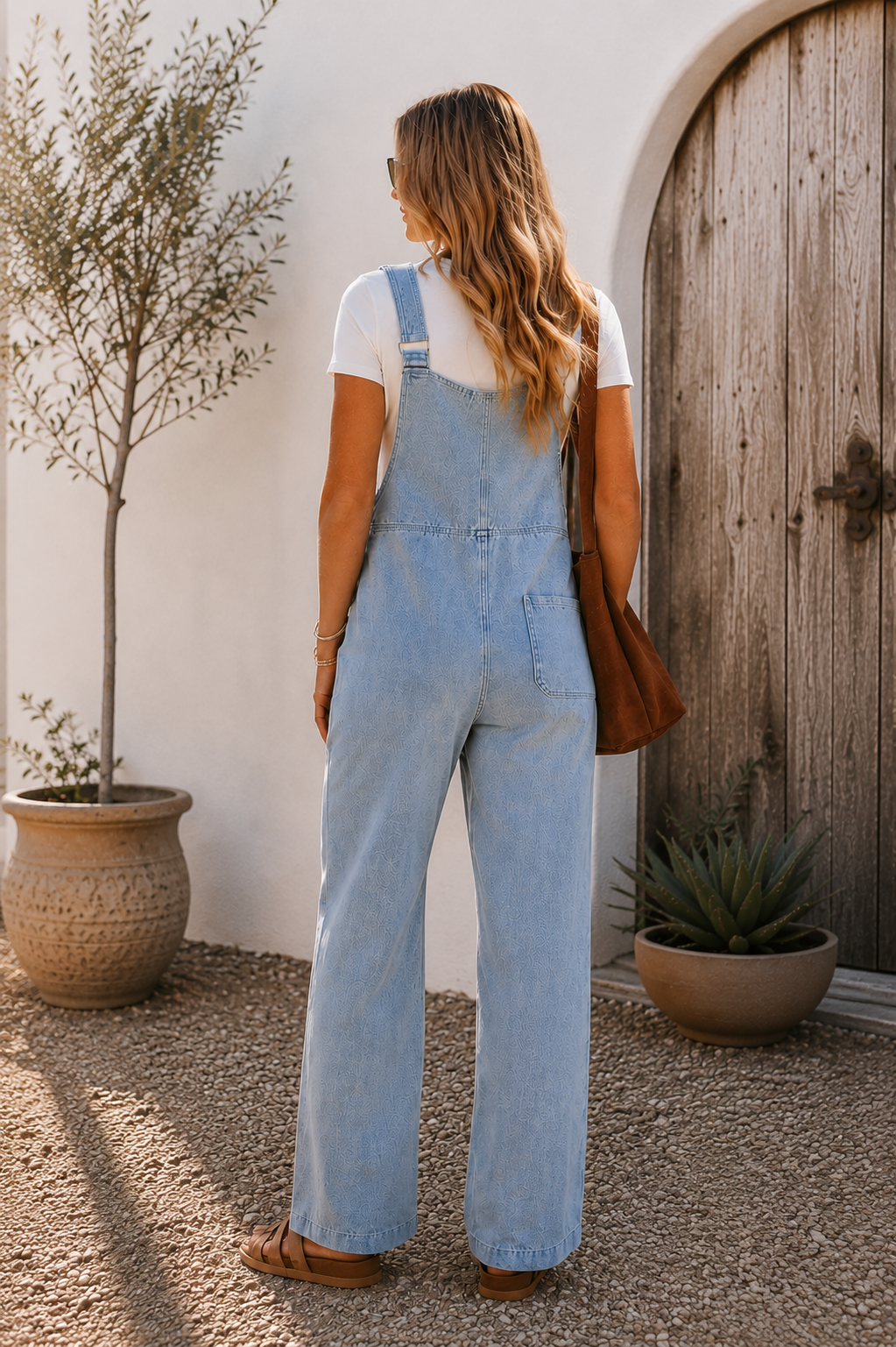 Women's light wash denim overall jumpsuit with wide legs, front patch pockets and utility seam detailing.