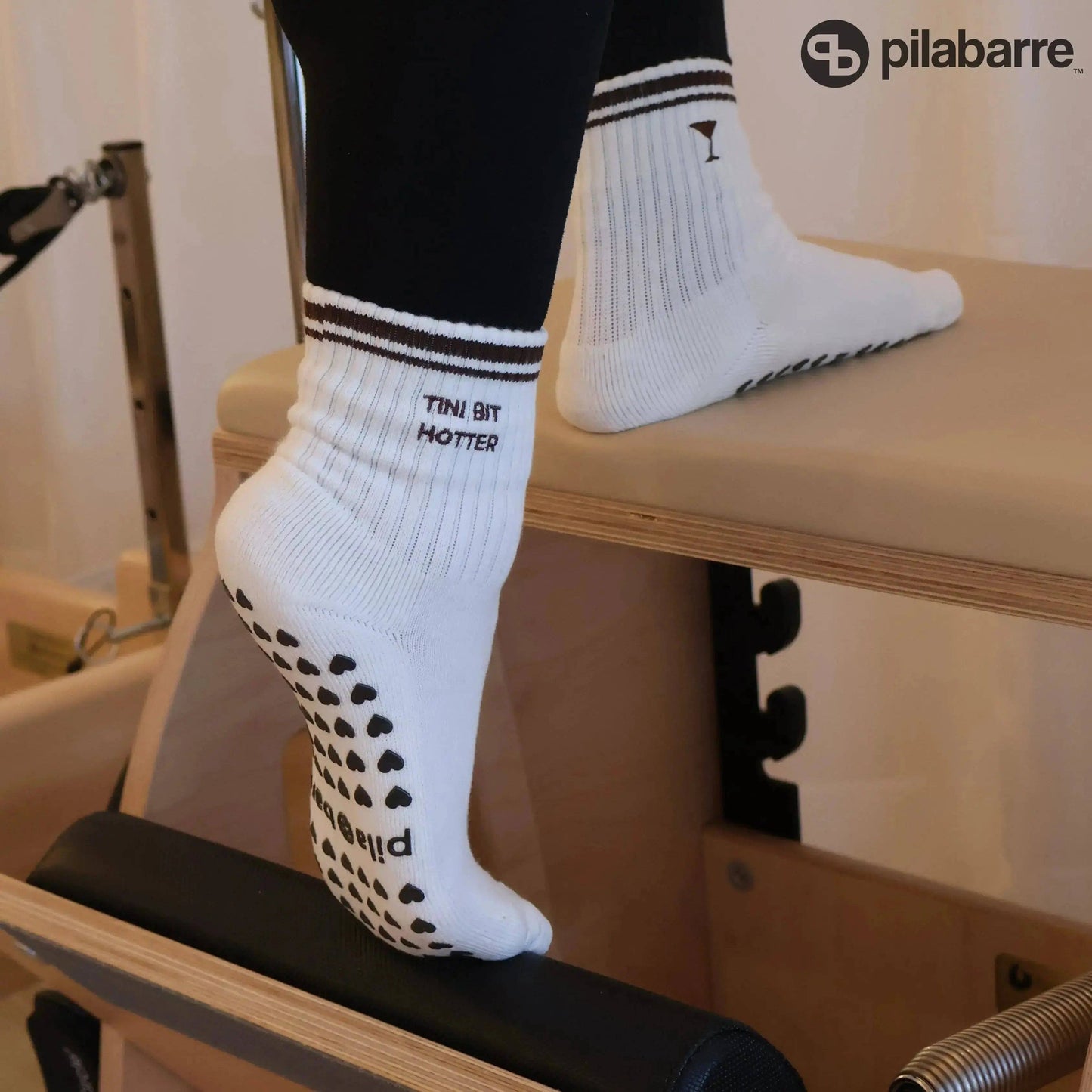 White Tiny Bit Hotter martini grip socks with contrast striped cuffs, cocktail embroidery and black heart-shaped non-slip grips.