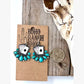 Turquoise western drop earrings featuring playing card designs and turquoise-inspired stone accents displayed on a rustic heart-shaped tray