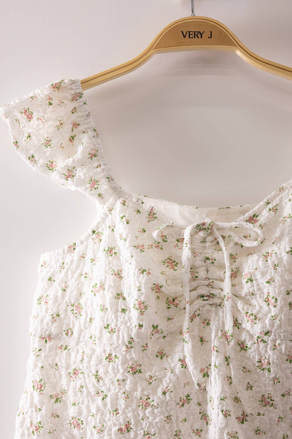 Blushing Prairie floral babydoll top available in blush and white with ruffle flutter sleeves and feminine tie-front neckline.